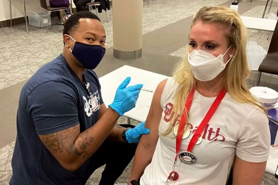 Publication co-author Eric Edwards, Pharm.D., who was a student at the University of Oklahoma College of Pharmacy at the height of the COVID-19 pandemic, vaccinates a college staff member.