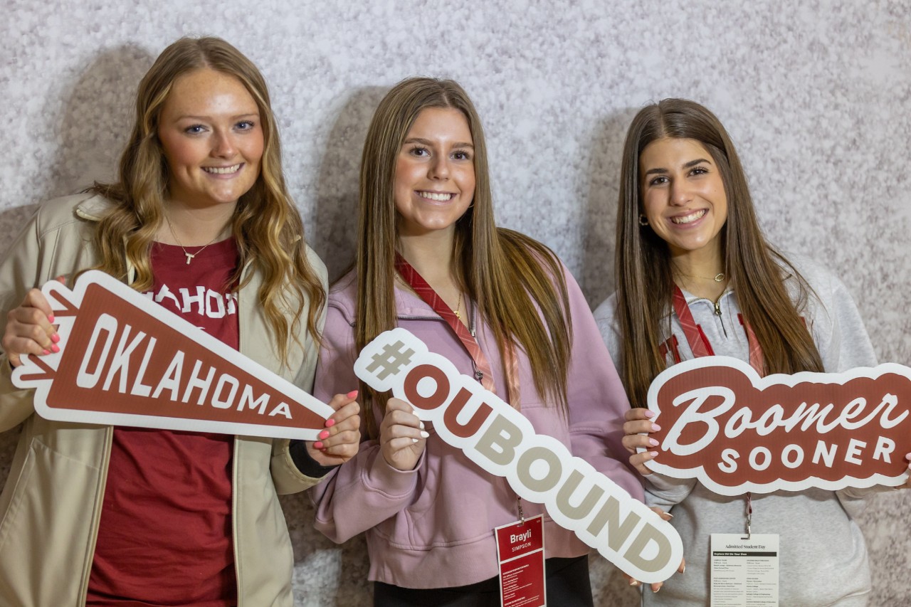 Three students at Admitted Student Day holding OU signs 