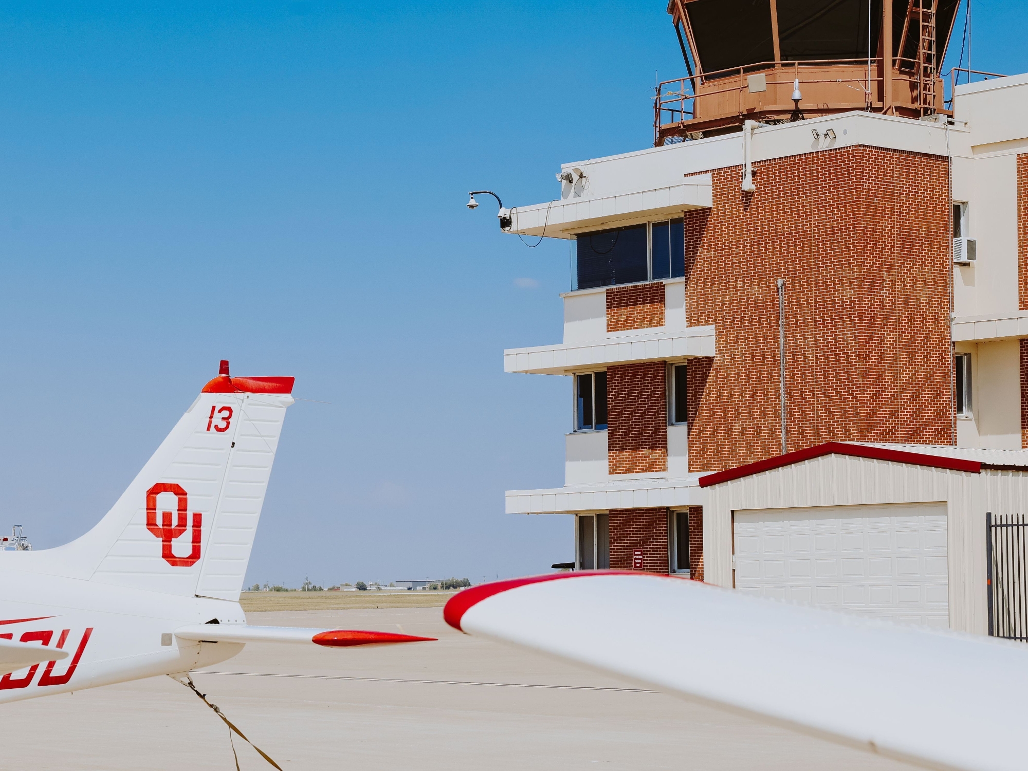 two aviation students inspecting the tailfin of the plane with the OU logo on the vertical shaft of the tailfin. 