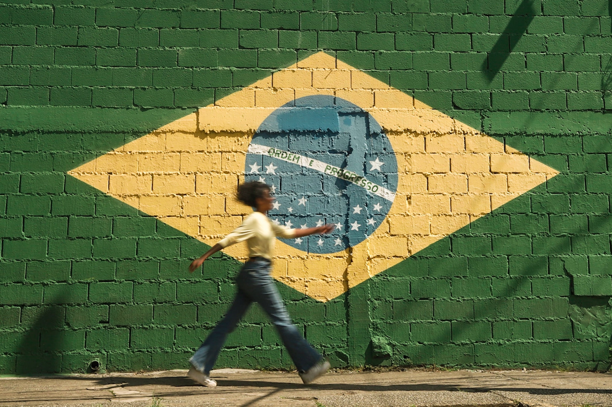 woman walks by Brazil flag.