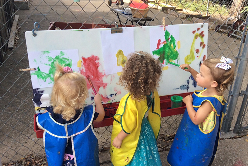 Three children standing at an easel, painting