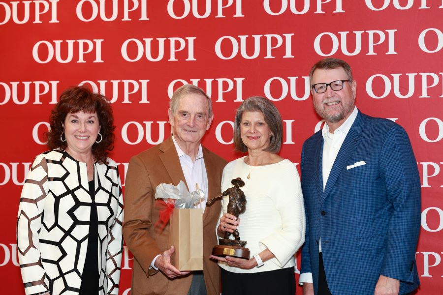 A group photo of OUPI leadership, the Carters, and OU Foundation leadership in front of the OUPI backdrop.