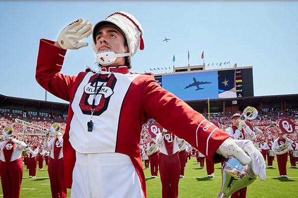 Band member saluting during the National Anthem as a jet flies over before OU vs UTEP football game
