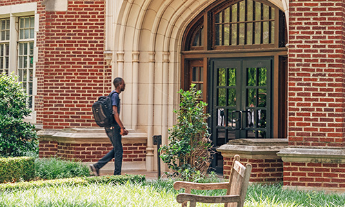 Decorative photo of OU student with a backpack on walking into a university building
