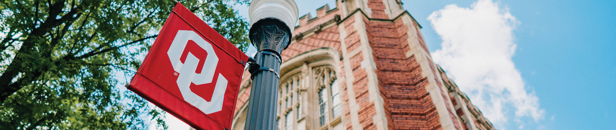 ou flag on lamp pole with brick building in the background