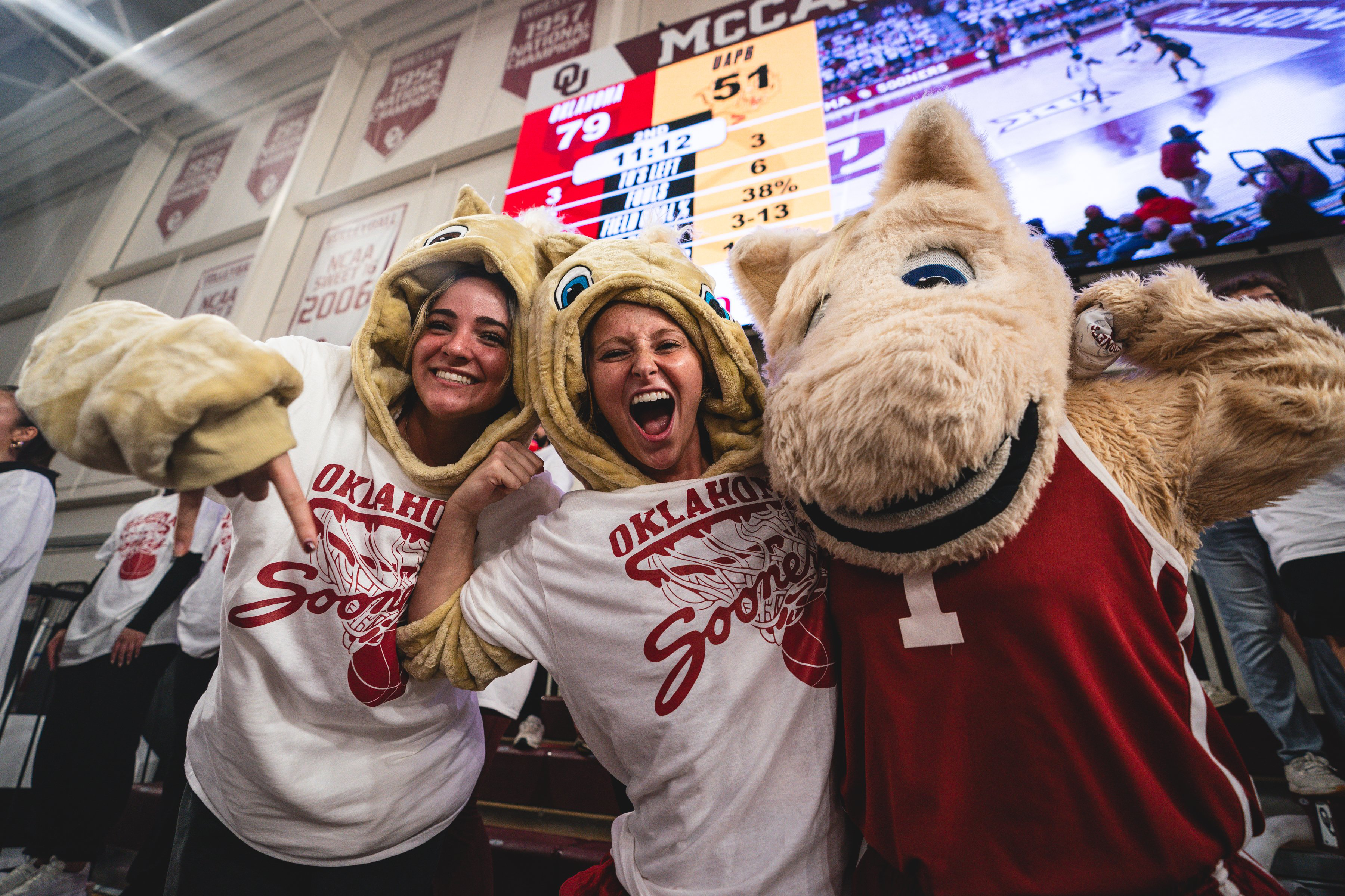Students cheering at a basketball game with one of OU's mascots.
