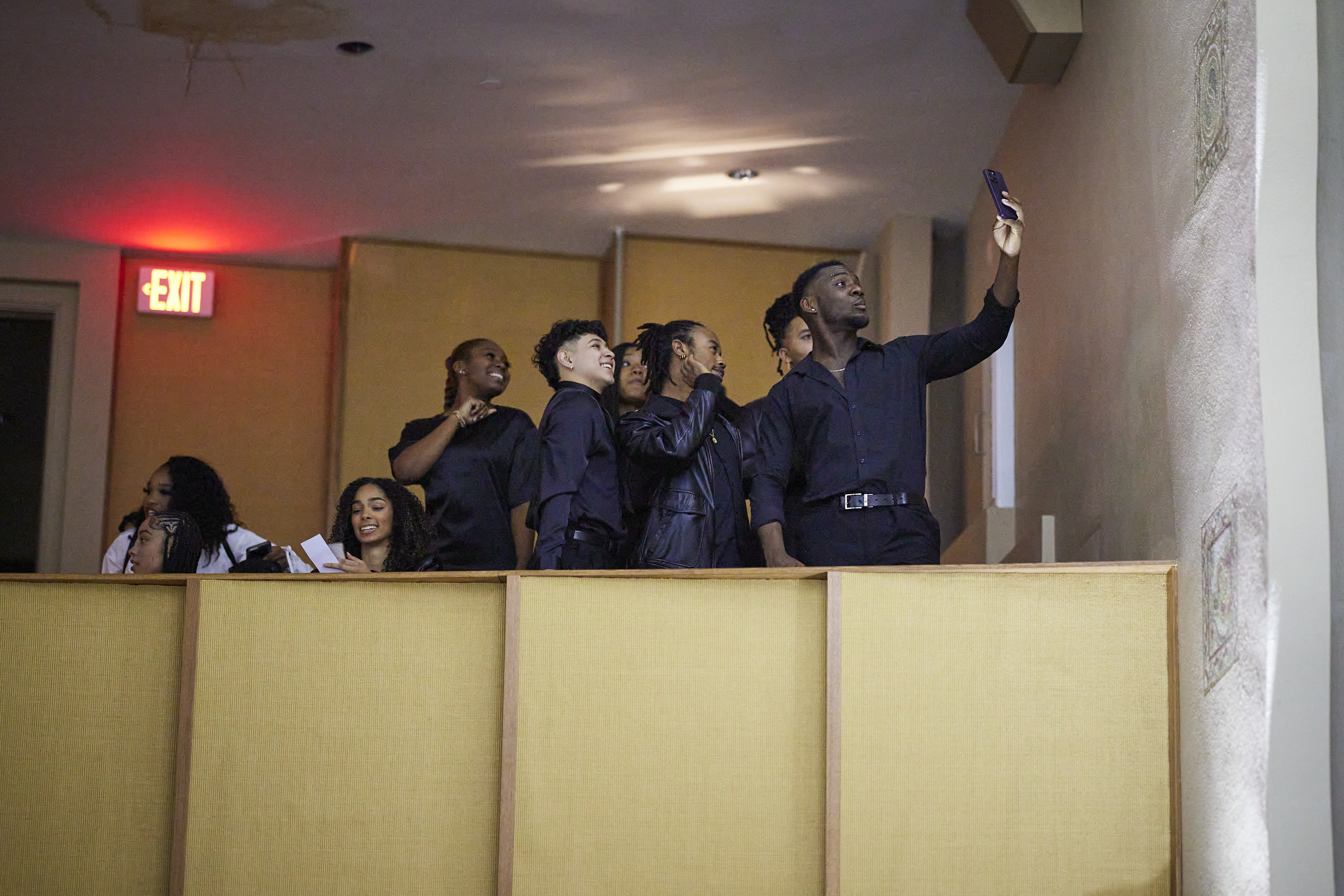 A group of students taking a selfie in the balcony of an auditorium at an event.