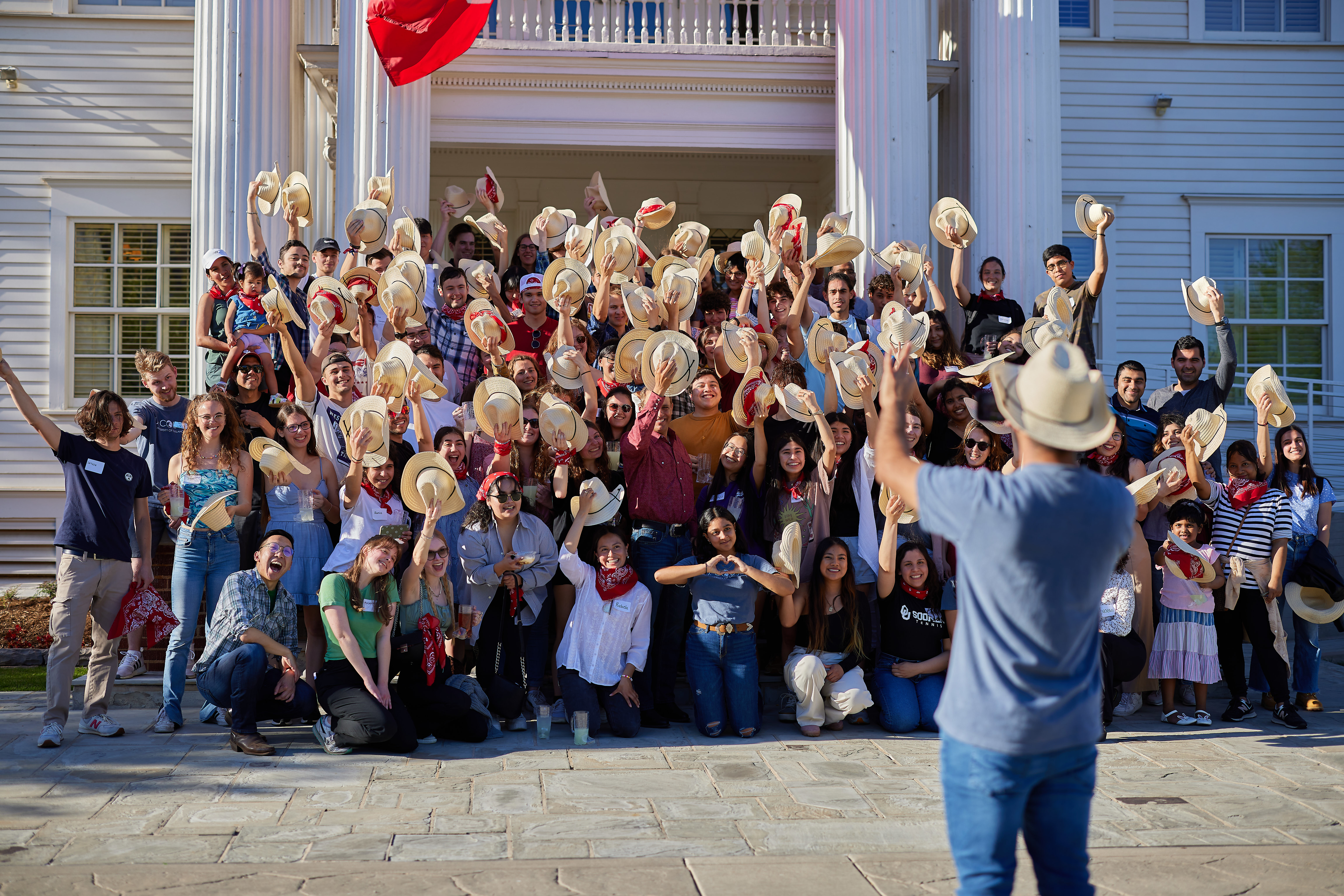 OU Cousins students waving cowboy hats in a group photo.