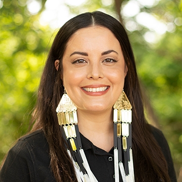 Woman with long dark hair wearing black shirt and long Native earrings.