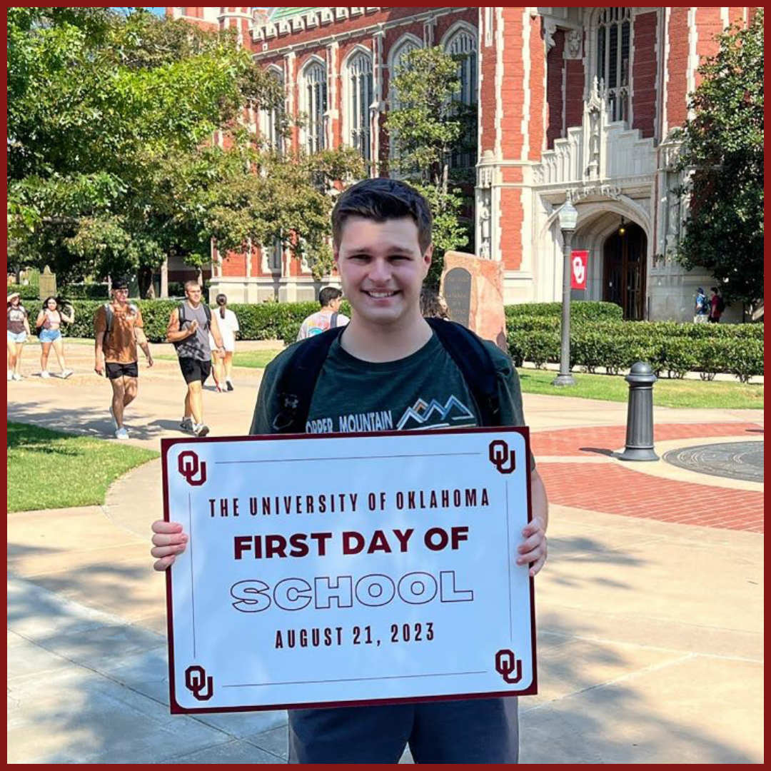 picture of Matt L smiling and holding a first day of school sign in front of Bizzell Library