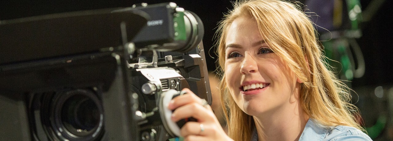 A Gaylord student works behind the camera in a studio