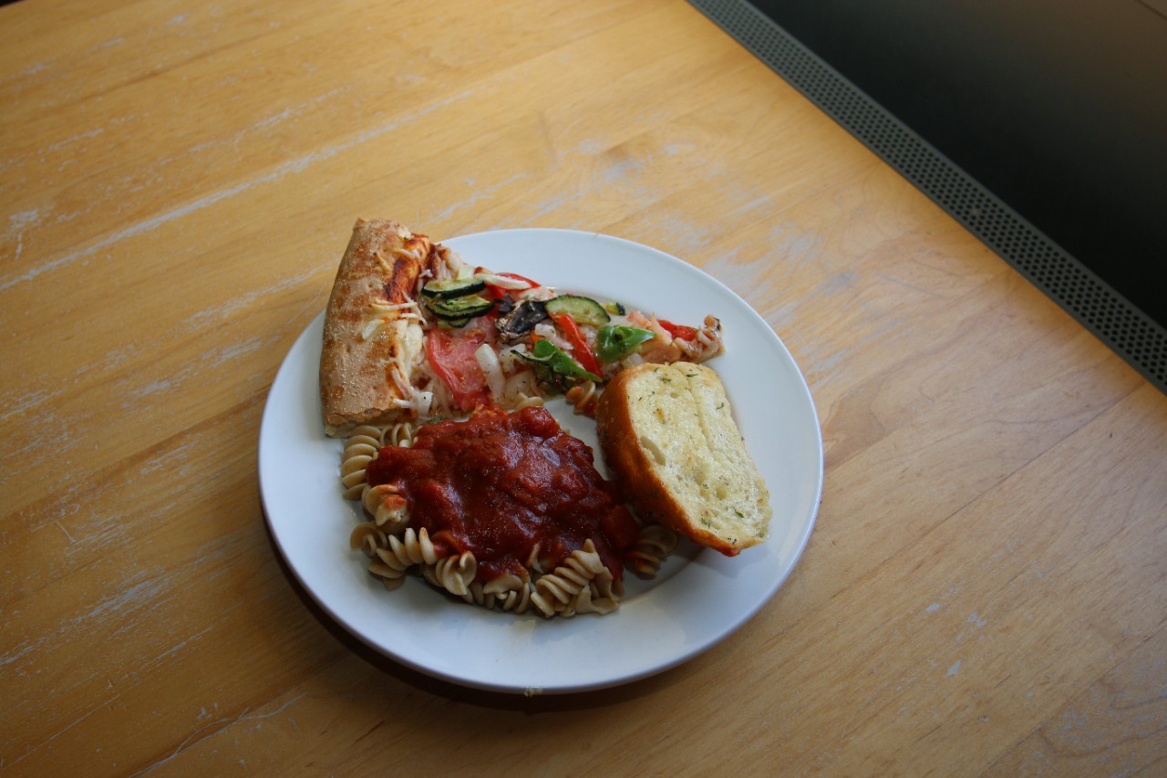 pizza, pasta and slice of bread on a plate sitting on a table
