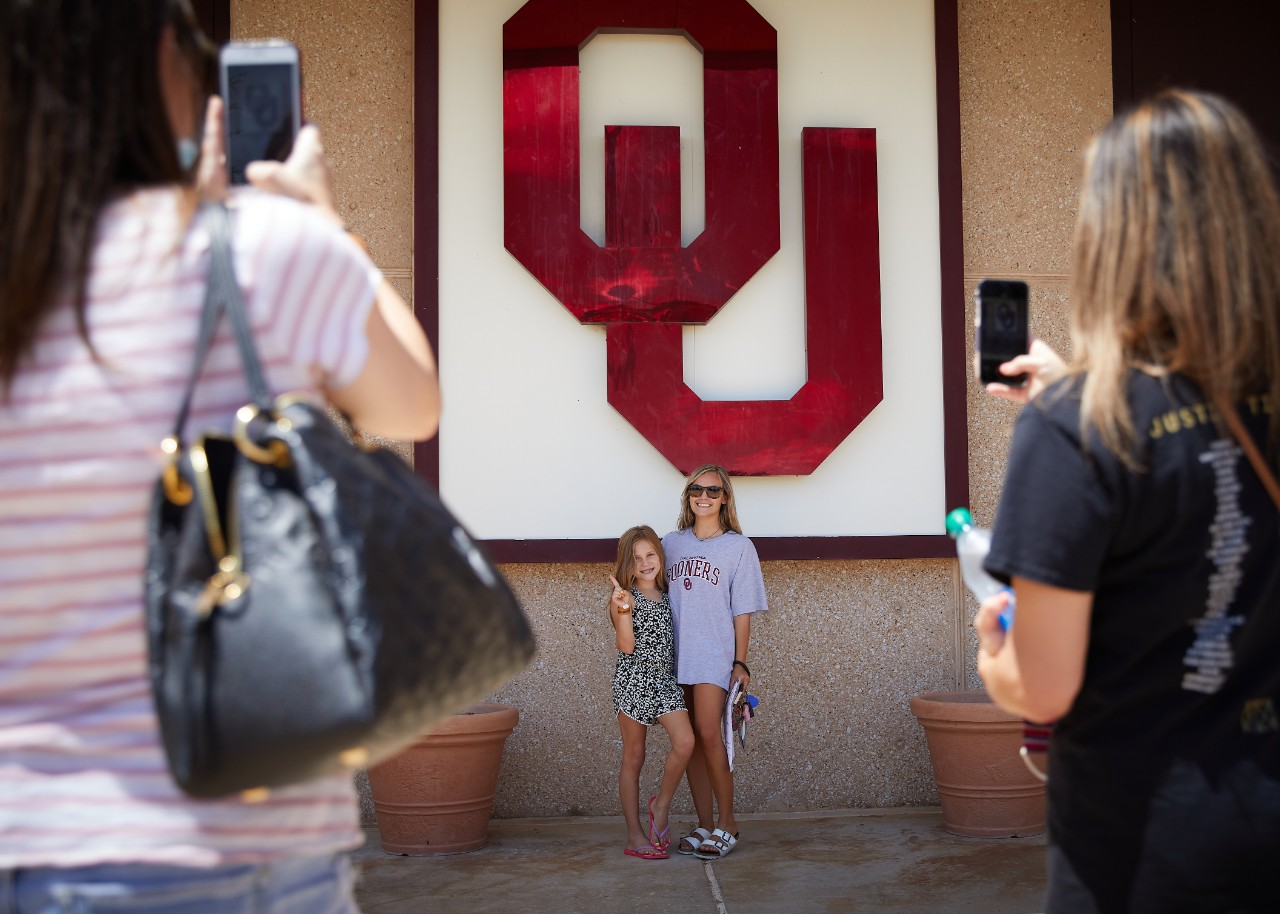 Two people stand in front of the Interlocking OU on LNC's outer wall to pose for a photo.