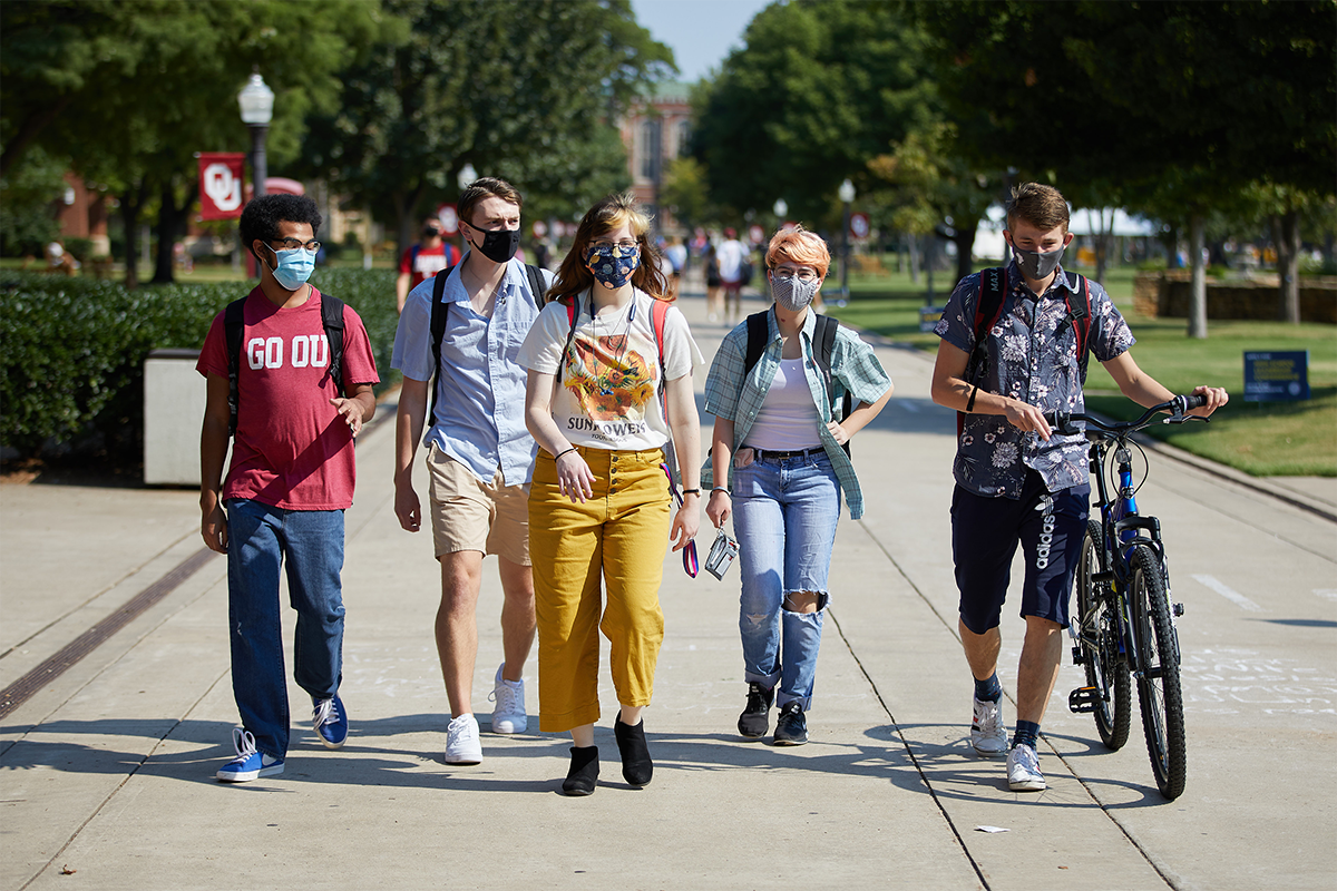 A group of students in masks walk down the south oval together