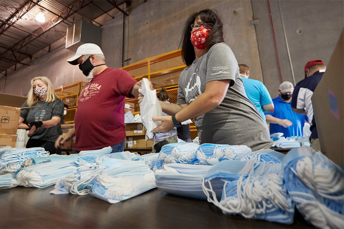 Masked volunteers help to assemble welcome kits
