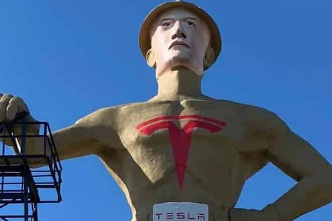 Golden Driller statue with Tesla Logo painted scross its chest
