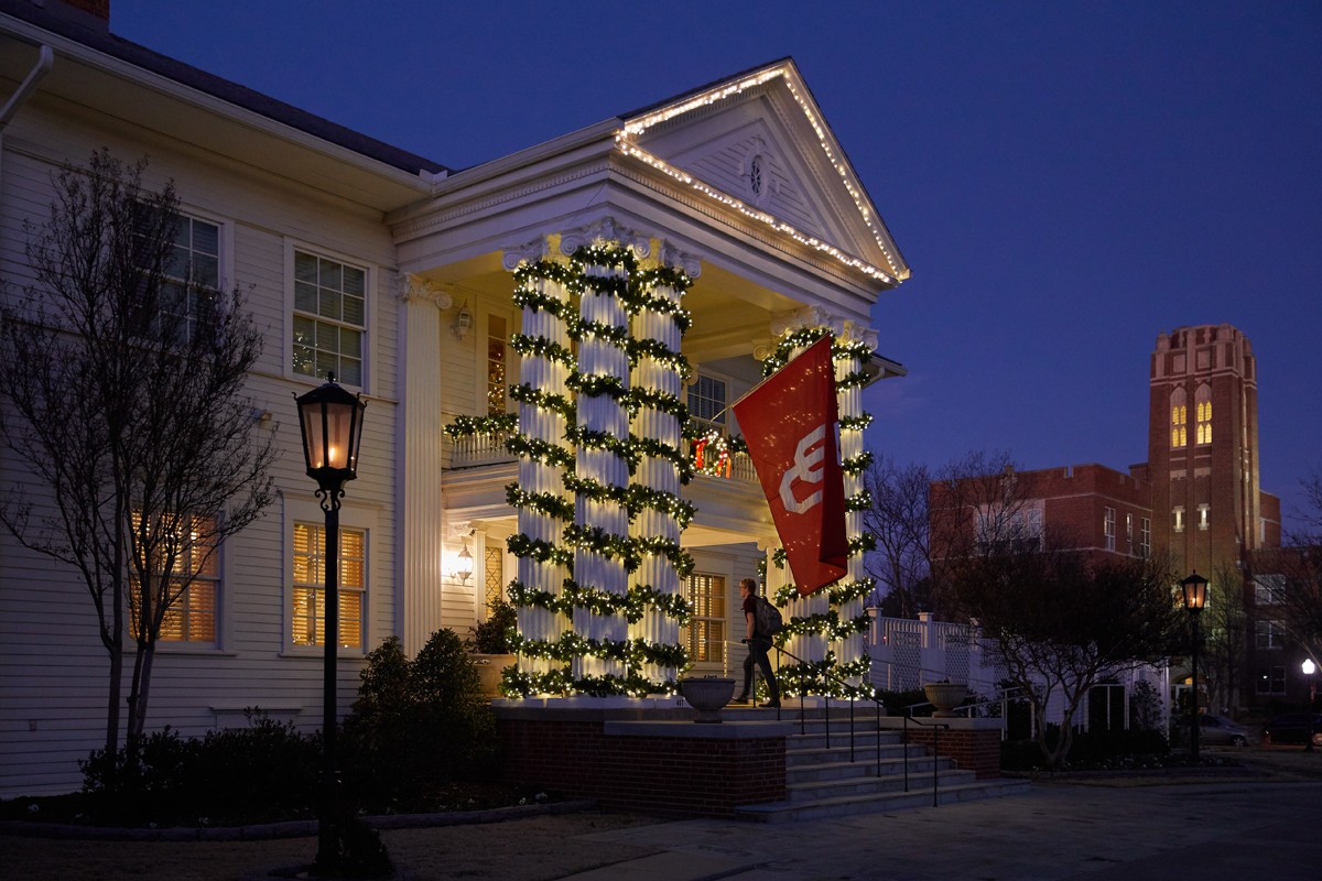 night shot of Boyd House decoared with lights and garland
