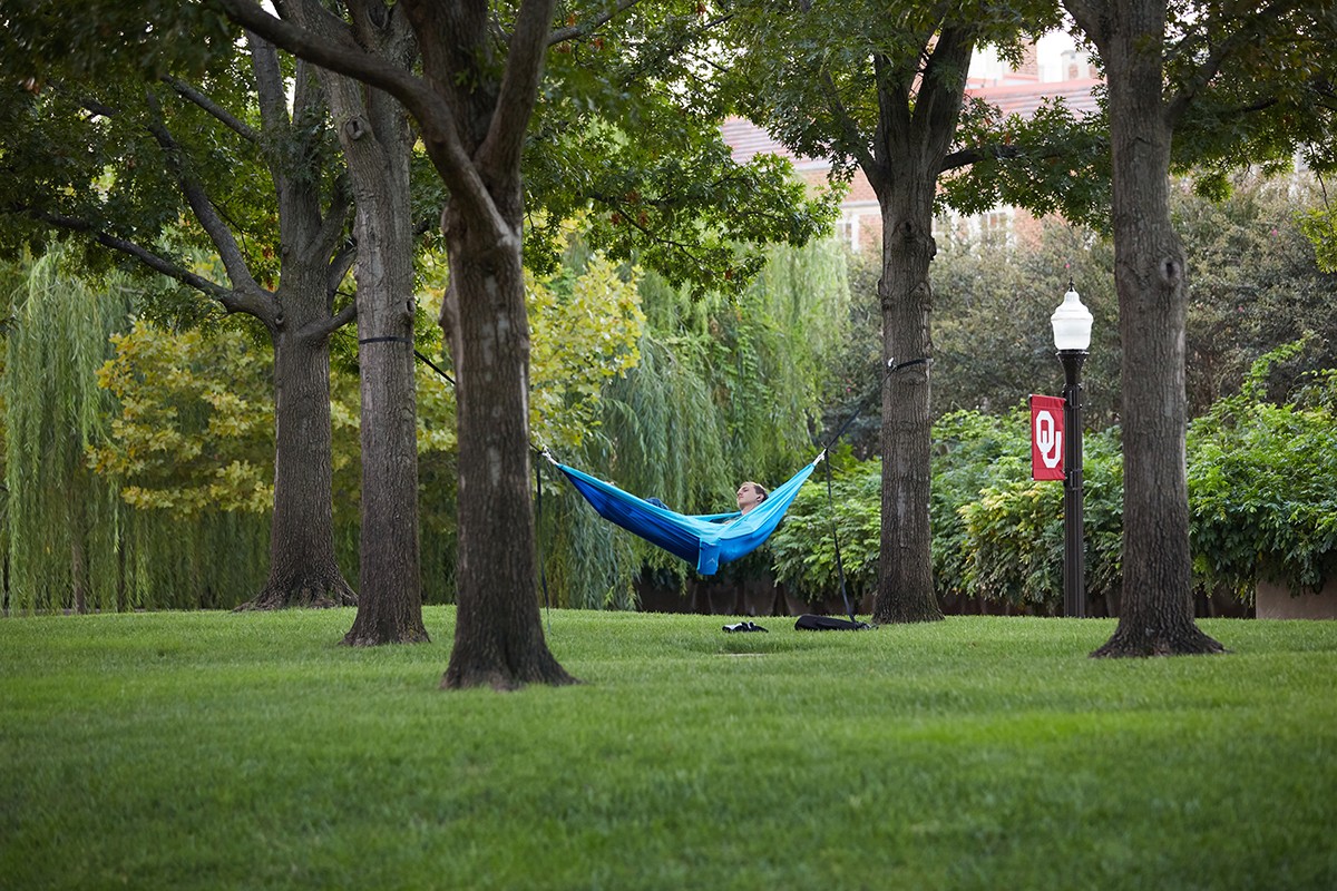 student relaxes in hammock on campus