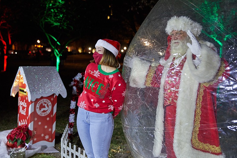 santa poses with a student from inside a protective bubble