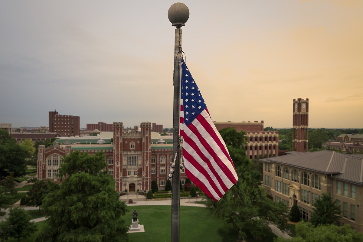 American flag atop a flagpole over OU campus at sunrise