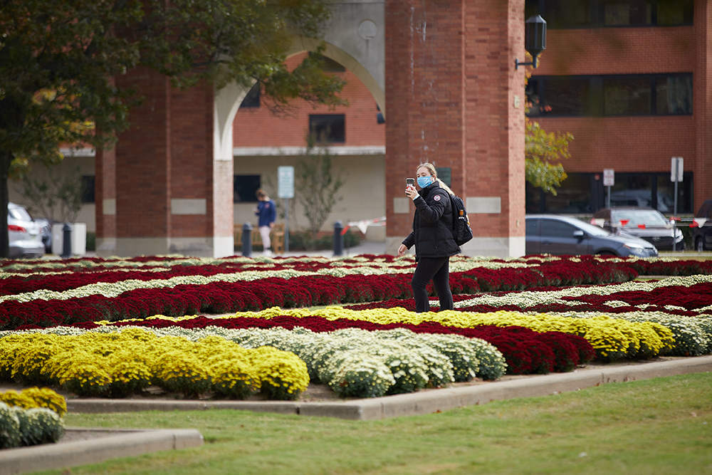 An OU Students snaps a cell phone photo of the flowerbeds