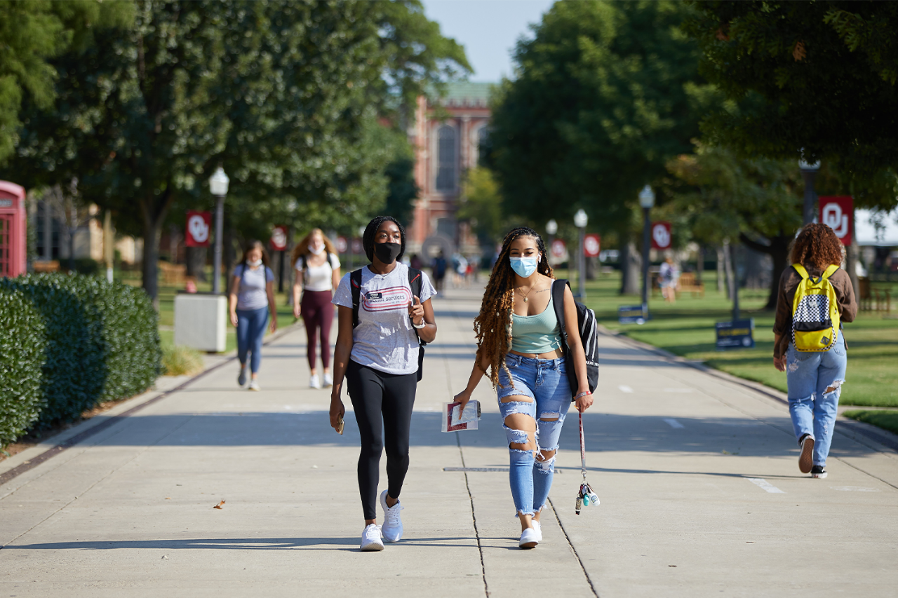 two students wearing COVID masks walk on the South Oval