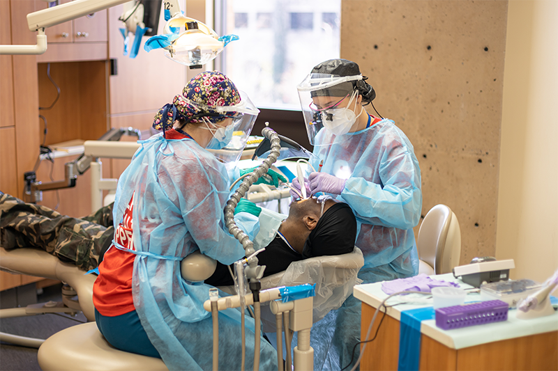 Masked dental technicians provide care to an OU community member