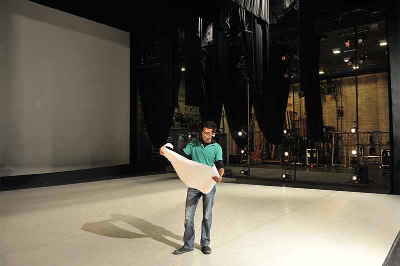 Honore holds a large, print lighting design back stage
