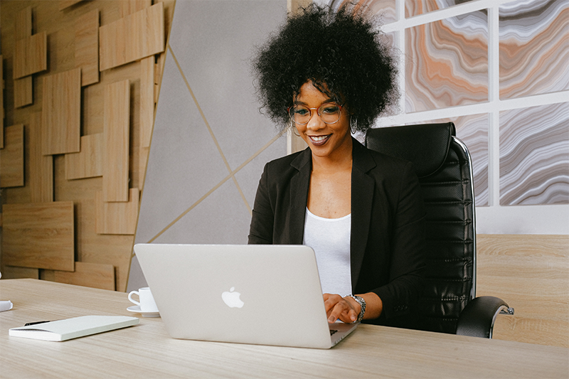 Stock photo a black woman uses a laptop in an office setting
