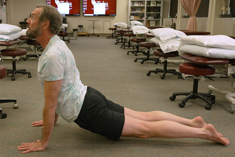 Still from the Youtube video, a man mid yoga routine, cobra pose
