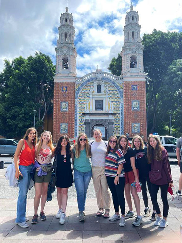 students posed together outside stone historic church building in Mexico