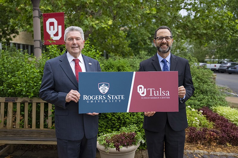OU-Tulsa President Dr. John H. Schumann and RSU President Dr. Larry Rice pose together holding a sign with both college logos