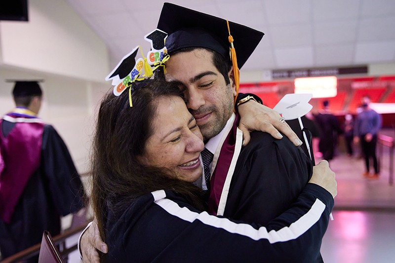 Student in regalia embraces loved one at LNC graduation