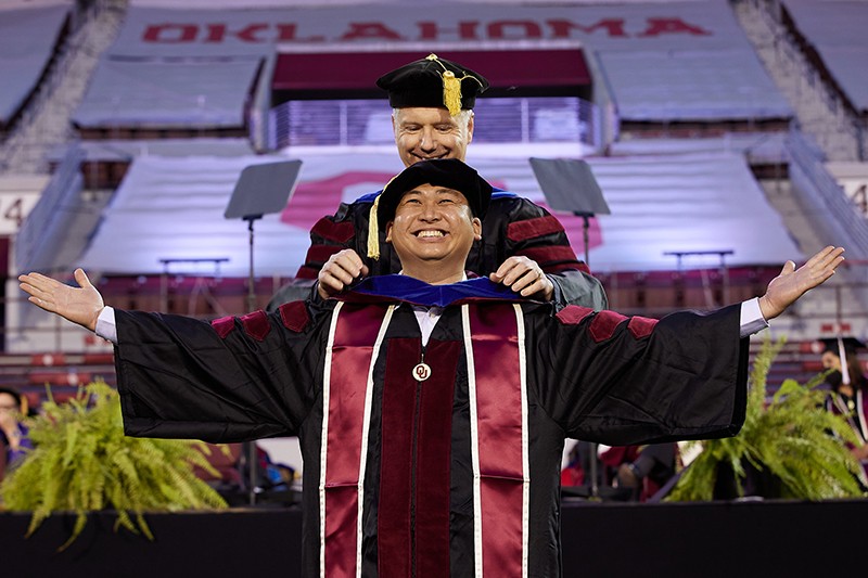 Student is hooded by professor at commencement