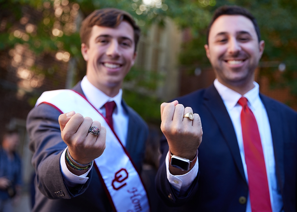 two students post with class rings on hands