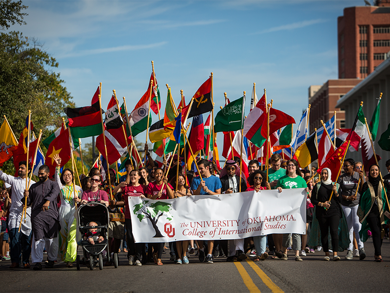 College of International studies students holding many national flags march in a parade