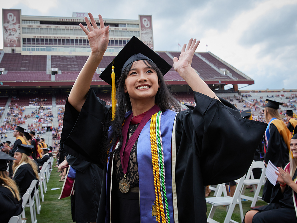 A graduating student waves to the stands at 2021 Graduation