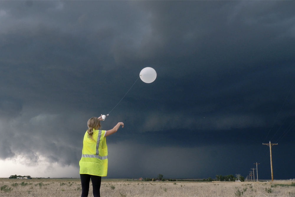 Student releases a weather balloon as storm clouds loom in the background