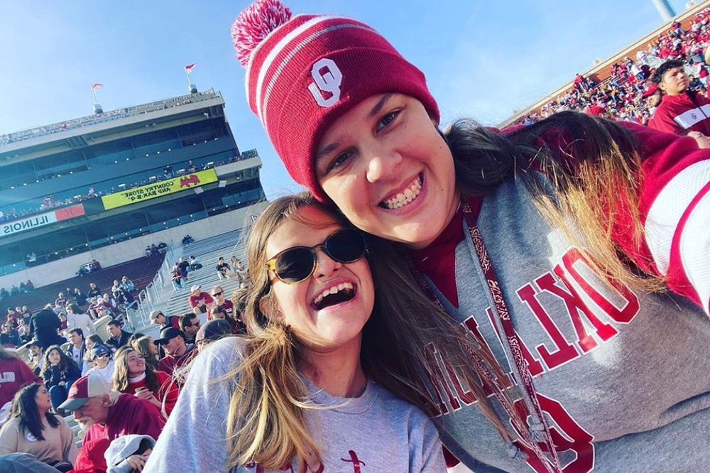 Grace Medina and Madison Mason smile together in the stands at an OU football game.