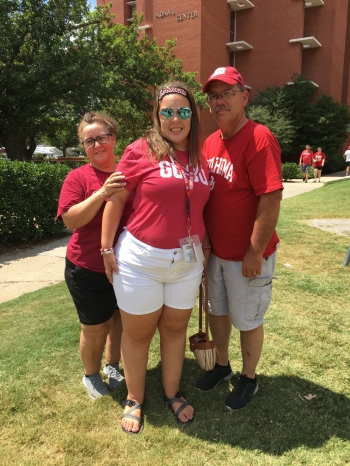  Madison Mason and her parents stand together smiling on the OU campus.