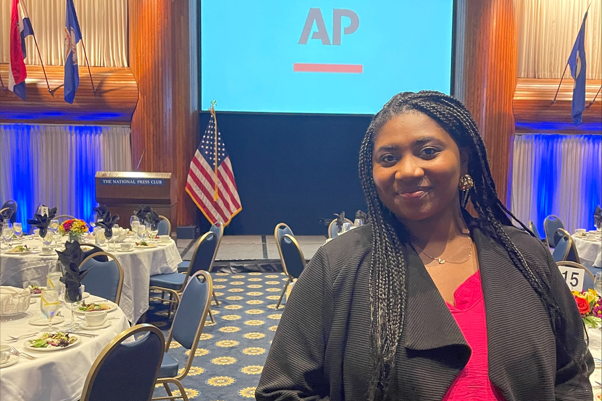 Zaria Oates poses in front of a screen with the AP logo at an event
