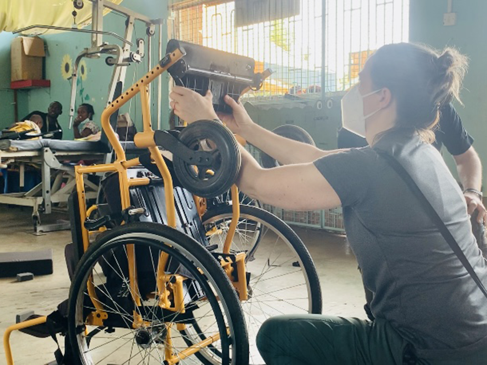 Student adjusts wheelchair at clinic