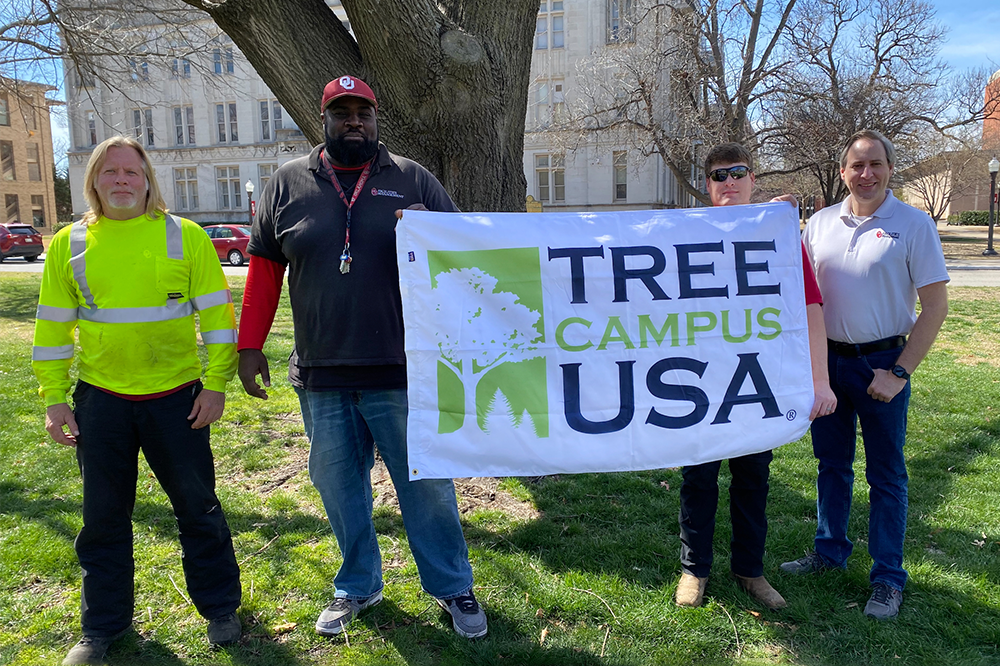 Staff pose with Tree Campus USA banner on the North Oval
