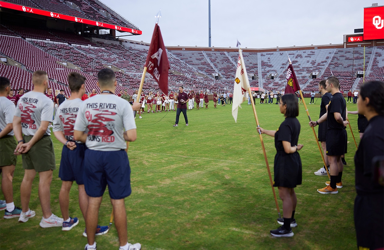 NROTC students stand in the stadium, holding flags