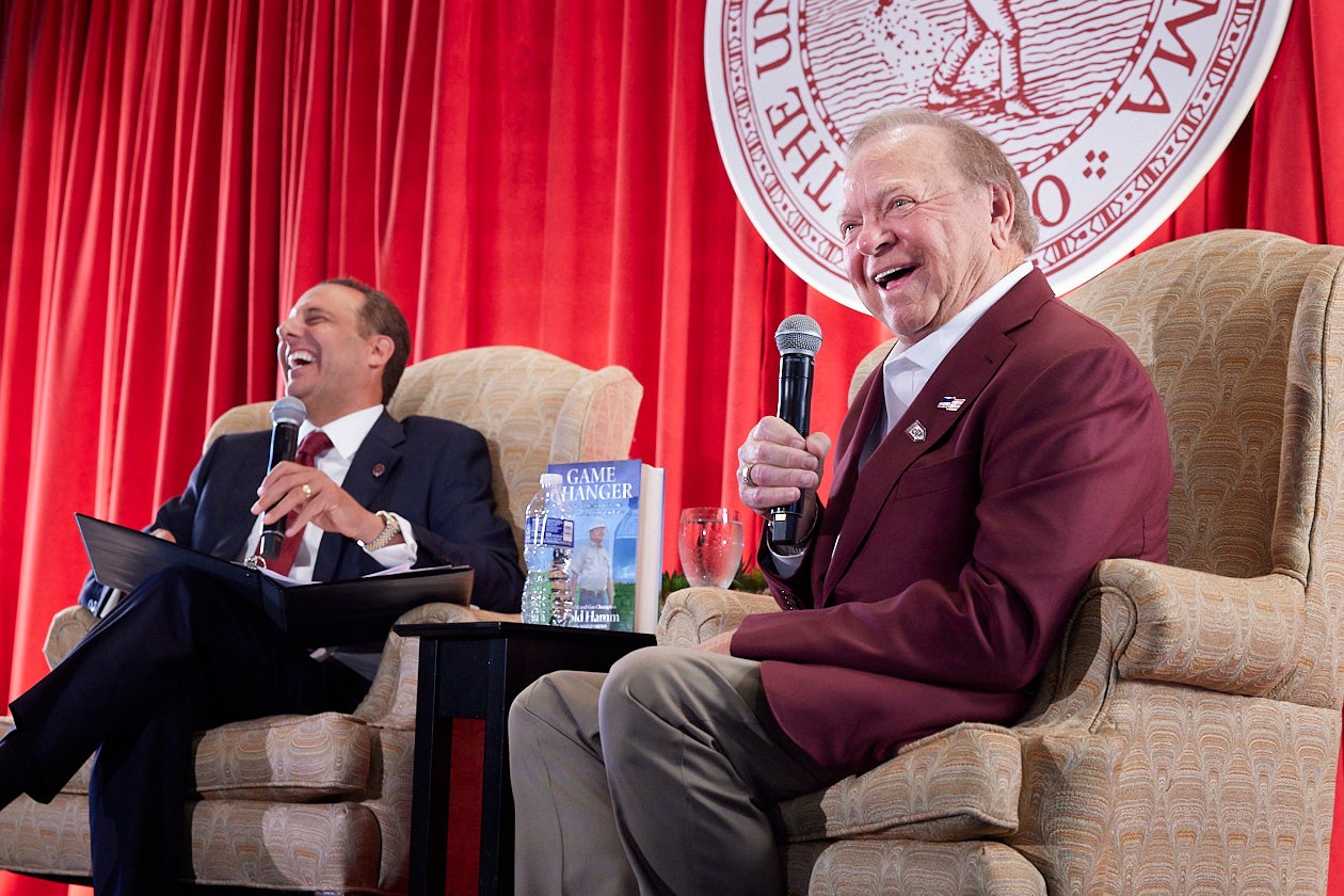 Harold Hamm speaks with President Harroz at the event, both laughing
