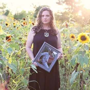 Atwell in a field holding a framed photo of her son, Clay.