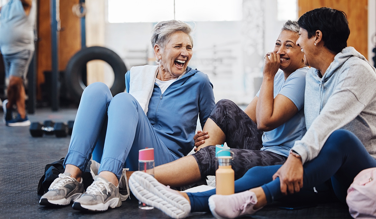 decorative image of people sitting on the floor in a fitness class and laughing