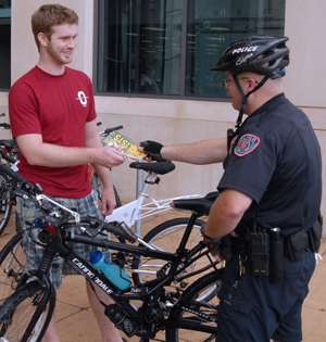 MPO Jay Littlejohn hands a bike safety brochure to an OU student.