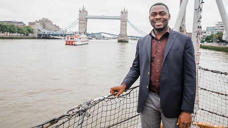 Executive MBA in Energy student pictured on a boat on the River Thames with London Bridge in the background. 