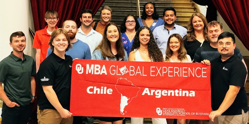 Students hold a sign which reads "OU MBA Global Experiences, Chile Argentina. Price College of Business Gene Rainbolt Graduate School of Business, The University of Oklahoma